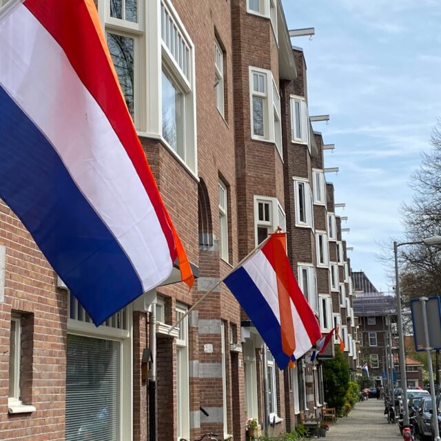 A row of brick buildings with flags hanging from the windows