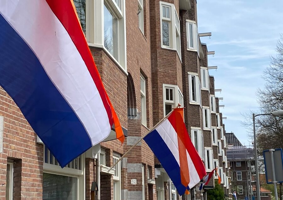A row of brick buildings with flags hanging from the windows