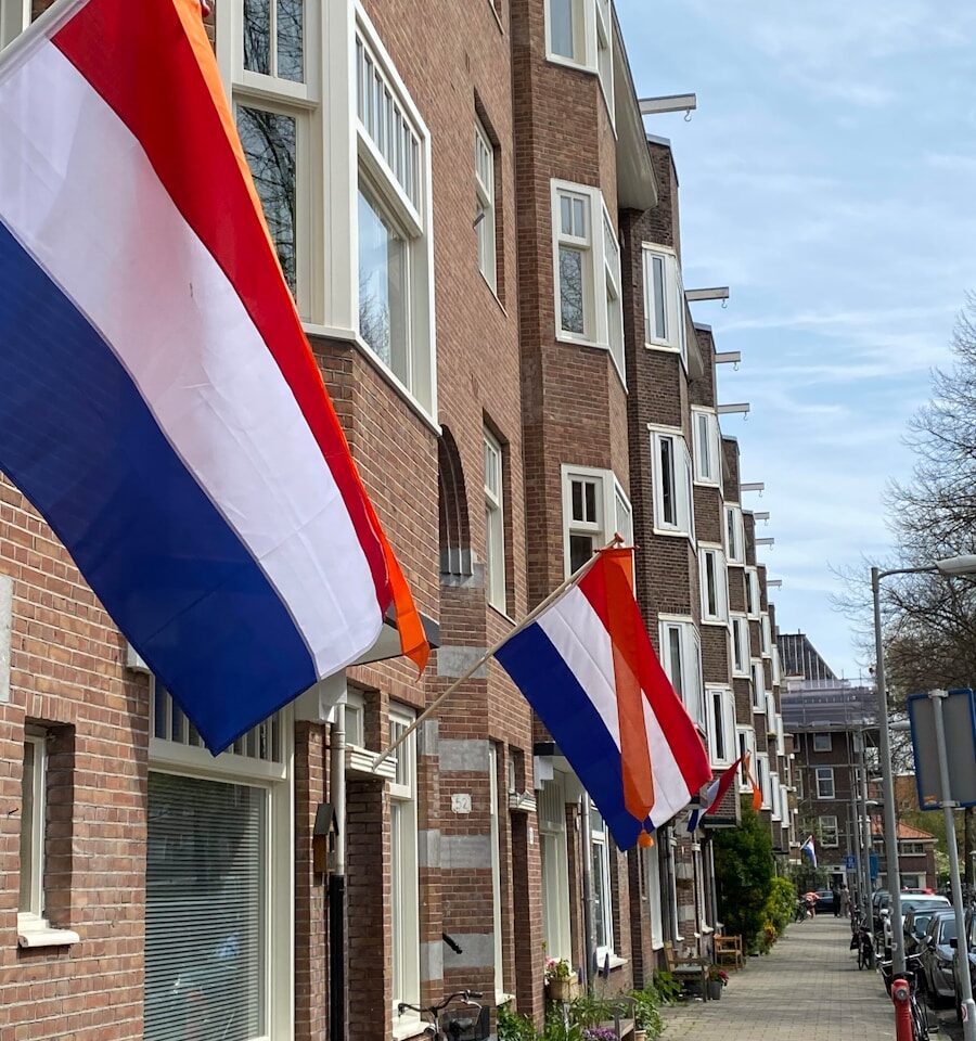 A row of brick buildings with flags hanging from the windows